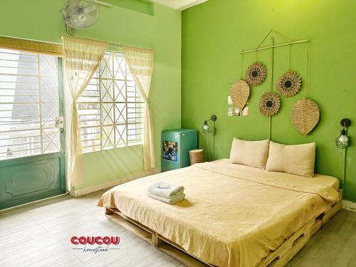 a bedroom with a bed with green walls and a window at Coucou Homestead I - Homestay & Dorm District 1 in Ho Chi Minh City