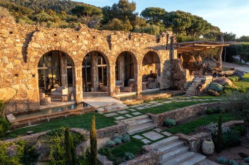une ancienne maison en pierre avec un jardin en face dans l'établissement Domaine Les Oliviers de Palombaggia, à Porto-Vecchio