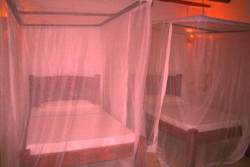 two beds in a room with pink curtains at Watamu Villa With Service Personnel in Watamu