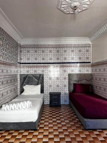 een slaapkamer met 2 bedden en een muur met tegels bij Medina Stars in Rabat