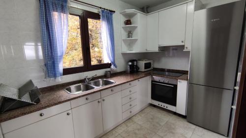a kitchen with white cabinets and a sink and a refrigerator at Autxikoborda in Elbete