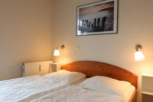 1 Schlafzimmer mit einem Bett mit weißer Bettwäsche und 2 Leuchten in der Unterkunft Strandstraße 14 - 51-1 in Kühlungsborn