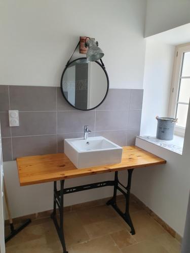 La salle de bains est pourvue d'un lavabo et d'un miroir sur une table. dans l'établissement Le nid d'oiseau, à Anché