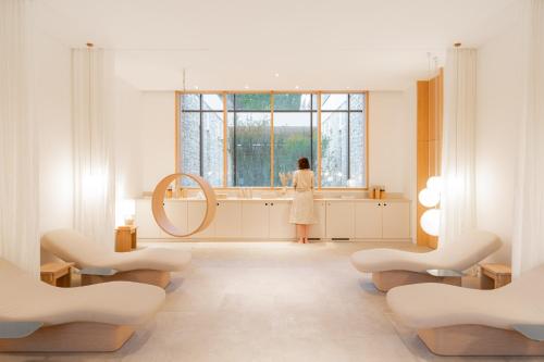 a woman standing in front of a mirror in a bathroom at Le Couvent des Minimes, un Hôtel & Spa L'Occitane en Provence in Mane