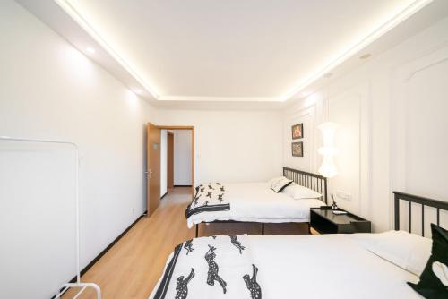 two beds in a room with white walls and wood floors at Shanghai Yi Du B&B - Family Suite 500m to Nanjing West Rd Near People's Square -Credit Cards Accepted in Shanghai