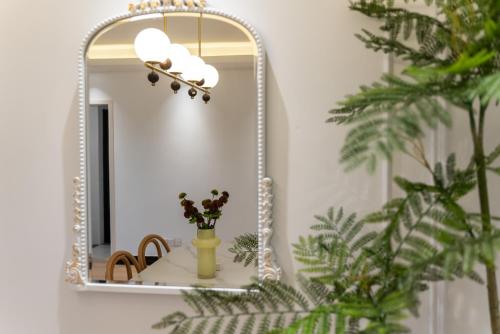 a mirror in a bathroom with a vase with flowers at Shanghai Yi Du B&B - Family Suite 500m to Nanjing West Rd Near People's Square -Credit Cards Accepted in Shanghai