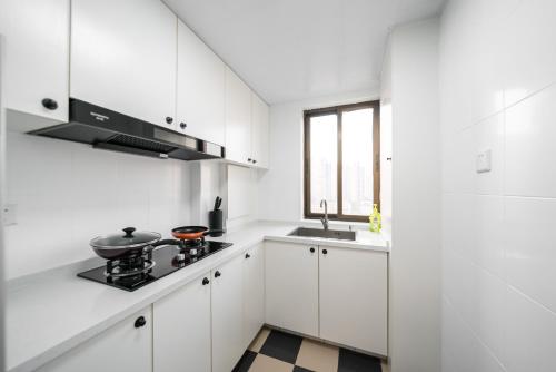 a white kitchen with a stove and a sink at Shanghai Yi Du B&B - Family Suite 500m to Nanjing West Rd Near People's Square -Credit Cards Accepted in Shanghai