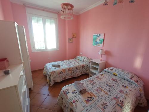2 camas en una habitación con paredes rosas en Casa La Romana, en Aracena