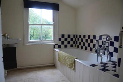 a bathroom with a bath tub and a window at Beautiful 18th Century Old Rectory with river in Norwich