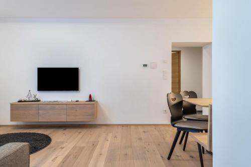 a living room with a tv on a white wall at Mountain Meadows Apt 4 in Valdaora