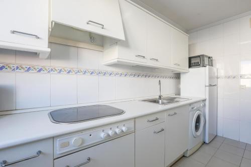 uma cozinha branca com um lavatório e uma máquina de lavar louça em Santa María 13 em Huelva