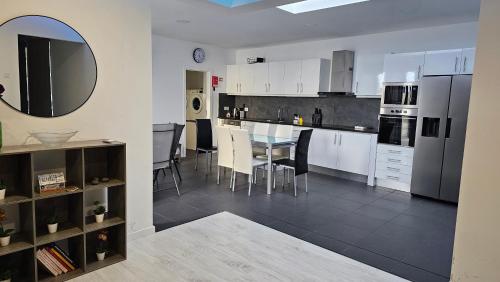 Una cocina con gabinetes blancos y una mesa con sillas. en Majestic Seaview Villa, en Fajã da Ovelha