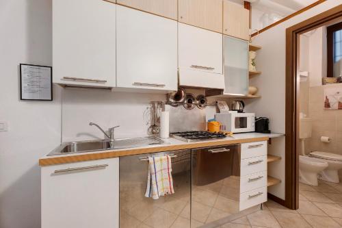 a small kitchen with white cabinets and a sink at Gigi House in Verbania