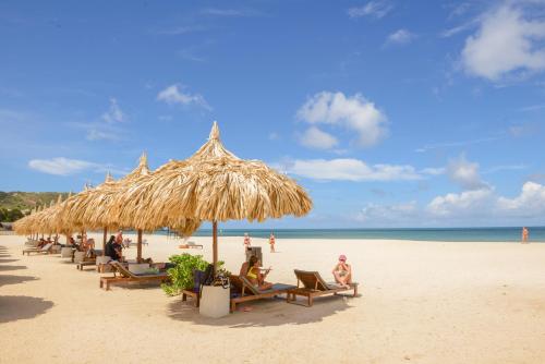 a beach with a bunch of chairs and a straw umbrella at Sunsol Ecoland in Pedro Gonzalez