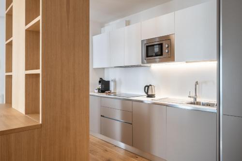 a kitchen with white cabinets and a microwave at Chalet Falorie in Cortina dʼAmpezzo