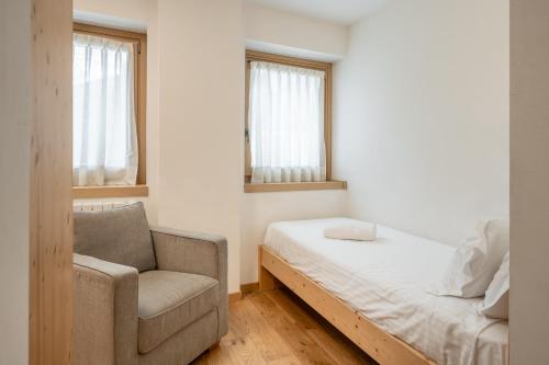 a small bedroom with a bed and a chair at Chalet Falorie in Cortina dʼAmpezzo