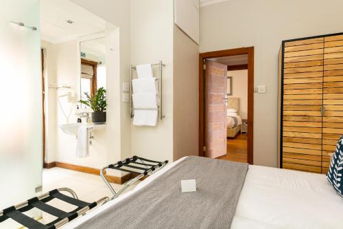 a bedroom with a bed and a bathroom with a mirror at Camps Bay Village in Cape Town