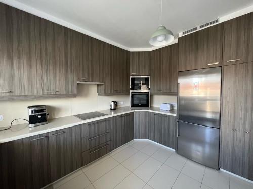 a kitchen with wooden cabinets and a stainless steel refrigerator at Majestic Boutique Apartment/2BR in Nicosia