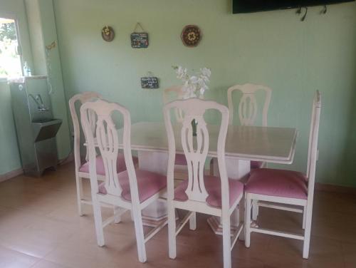 a dining room table with four chairs and a table with a glass top at Agencia e Pousada - Capitolio - MG in Capitólio