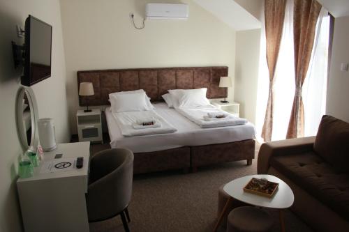 une chambre d'hôtel avec un lit et un canapé dans l'établissement sobe Astonia, à Subotica