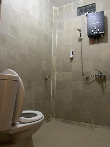 a bathroom with a toilet and a tv on the wall at Calliandra Homestay in Banyuwangi