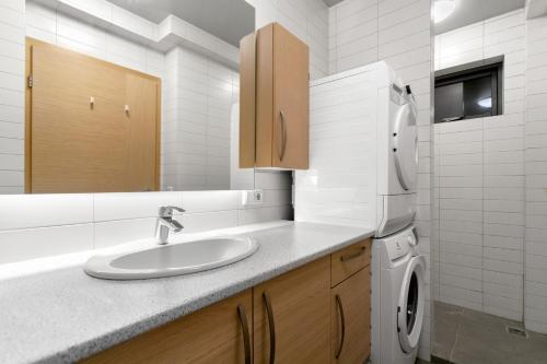 een badkamer met een wastafel, een wasmachine en een droger bij Downtown Apartments at Old Harbor Reykjavík in Reykjavík
