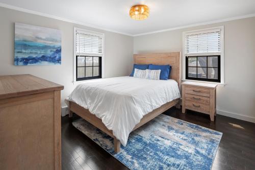 a bedroom with a bed and two windows at 3-min Walk To Beach! Private Luxury Backyard! in Dennis