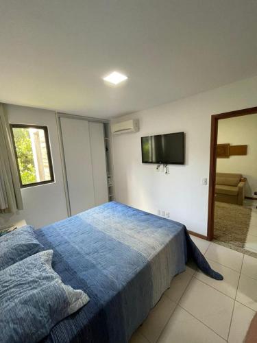 - une chambre avec un lit bleu et une télévision murale dans l'établissement ILOA RESIDENCE I APT 107K, à Barra de São Miguel