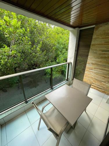 d'une table et de deux chaises sur un balcon avec une fenêtre. dans l'établissement ILOA RESIDENCE I APT 107K, à Barra de São Miguel