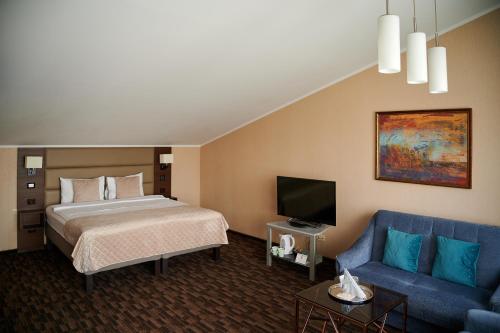 a hotel room with a bed and a blue couch at Olympus Hotel in Kaunas