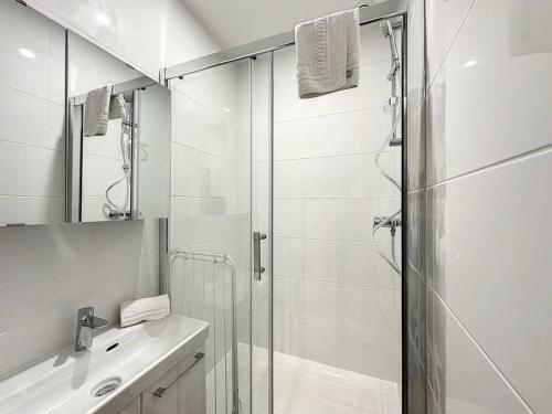 La salle de bains blanche est pourvue d'une douche et d'un lavabo. dans l'établissement Cosy appt, Centre de Lyon Bellievre 1, à Lyon