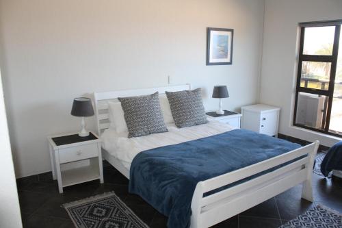 1 dormitorio con 1 cama blanca, 2 lámparas y ventana en Erf Three Seven Eight Langstrand Self-Catering en Langstrand