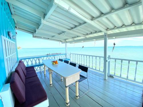 a balcony with a table and chairs on the beach at บ้านในทะเล (Baan Nai Talay) in Ban Ao Makham Pom