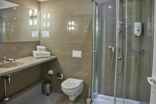 een badkamer met een douche, een toilet en een wastafel bij Olympus Hotel in Kaunas