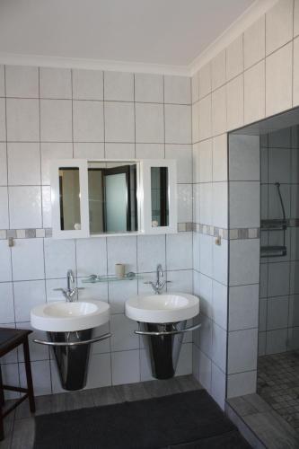 a bathroom with two sinks and two mirrors at Erf Three Seven Eight Langstrand Self-Catering in Langstrand