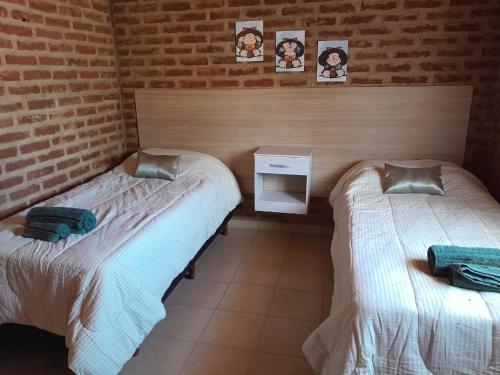 2 camas en una habitación con una pared de ladrillo en Cabaña Río Pulmarí en Aluminé