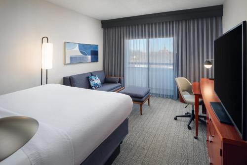 a hotel room with a bed and a chair and a television at Courtyard Columbus Worthington in Worthington