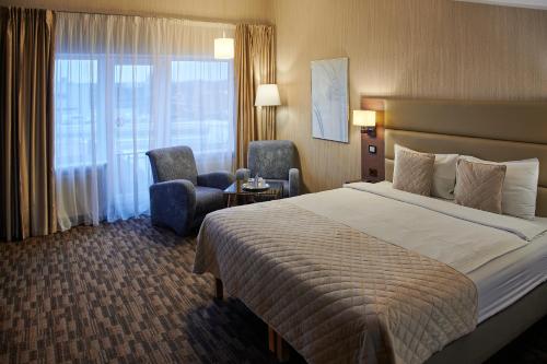 a hotel room with a large bed and a chair at Olympus Hotel in Kaunas