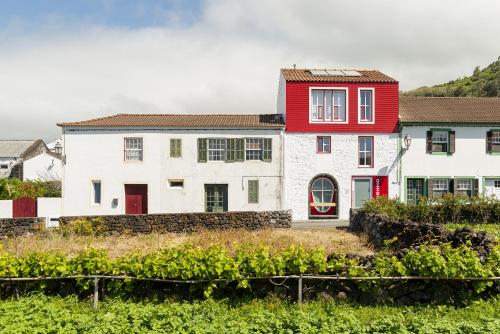 una casa con techo rojo y un campo de cultivos en Engenho Hostel en Lajes do Pico