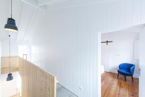 a hallway with a blue chair in a white room at Engenho Hostel in Lajes do Pico