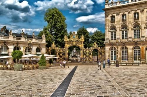 un grand bâtiment avec des gens qui marchent devant dans l'établissement Bienvenue à Nancy, à Nancy