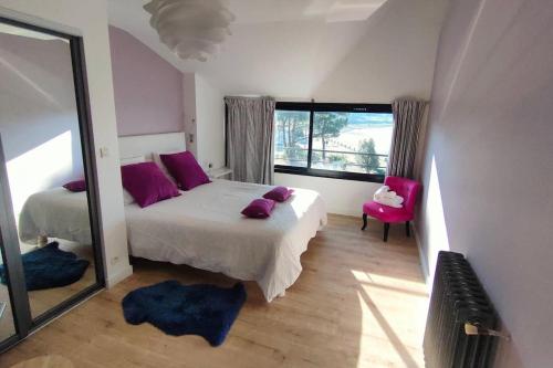 a bedroom with a bed with purple pillows and a mirror at Maison/Appart de standing vue mer in Guidel