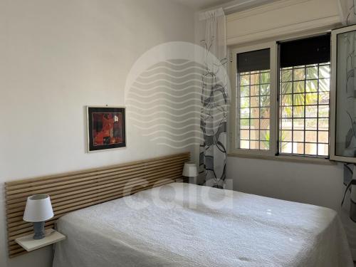 a bedroom with a white bed and two windows at Villa Nah - Spiaggia a 250m in Torre Lapillo