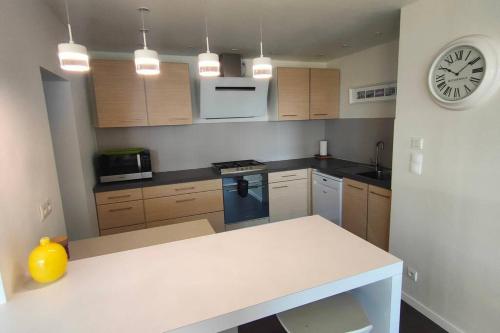 une cuisine avec un comptoir et une horloge au mur dans l'établissement Maison/Appart de standing vue mer, à Guidel