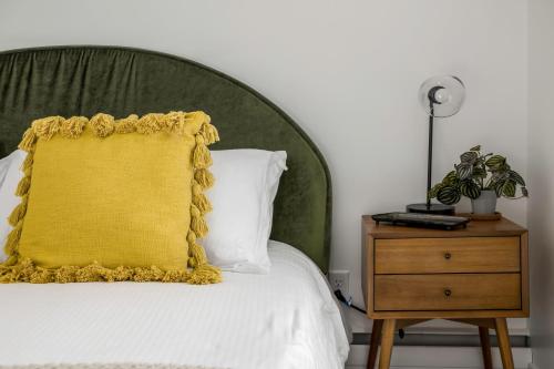 a bed with a yellow pillow and a night stand at Renovated 3BD 2BA Escape w Hot Tub and City Views in Salt Lake City