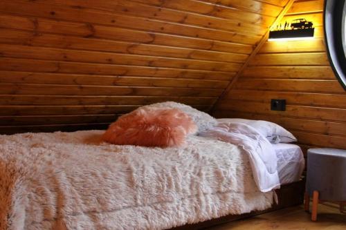 uma cama num quarto com uma parede de madeira em Katskhi Cottage, Your Cozy Stay em Katsʼkhi
