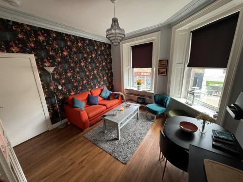 uma sala de estar com um sofá laranja e uma mesa em Edinburgh TWO BEDROOM apartment with free side street parking 24 hours em Edimburgo