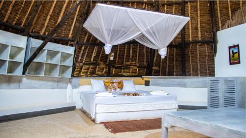 Zimmer mit einem Bett, einem Tisch und Vorhängen in der Unterkunft Le Grand Forest dreams Resort in Ukunda