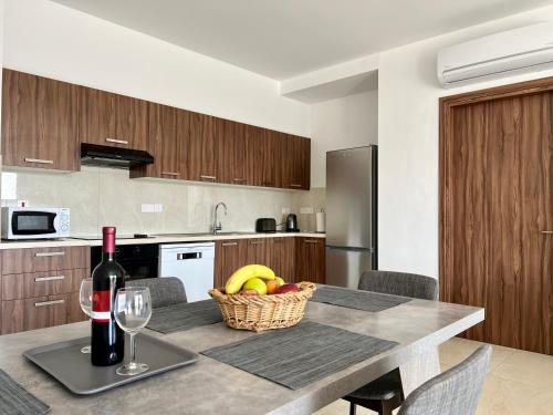 a kitchen with a table with a basket of fruit and a bottle of wine at Kings Boutique Apartment/2BR in Strovolos