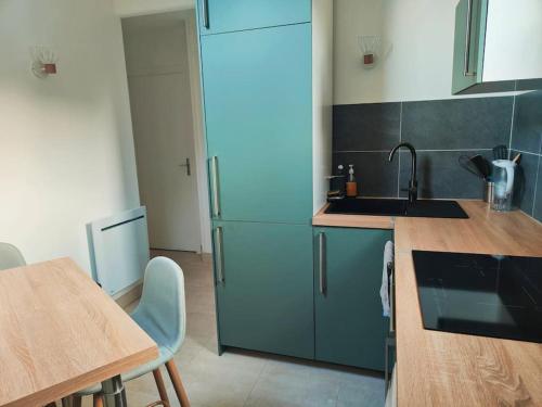 uma cozinha com armários azuis e uma mesa de madeira em Cosy, central et convivial em Trouville-sur-Mer